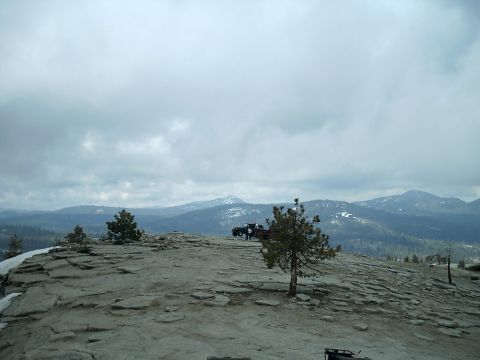 1989 Ford Bronco - Vehicles are parked on a high, rocky terrain with expansive mountain views and a cloudy sky.