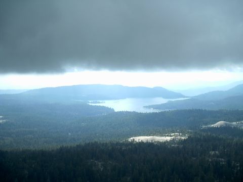 1989 Ford Bronco - A vast landscape of mountains and a lake is visible under a heavy cloud cover.