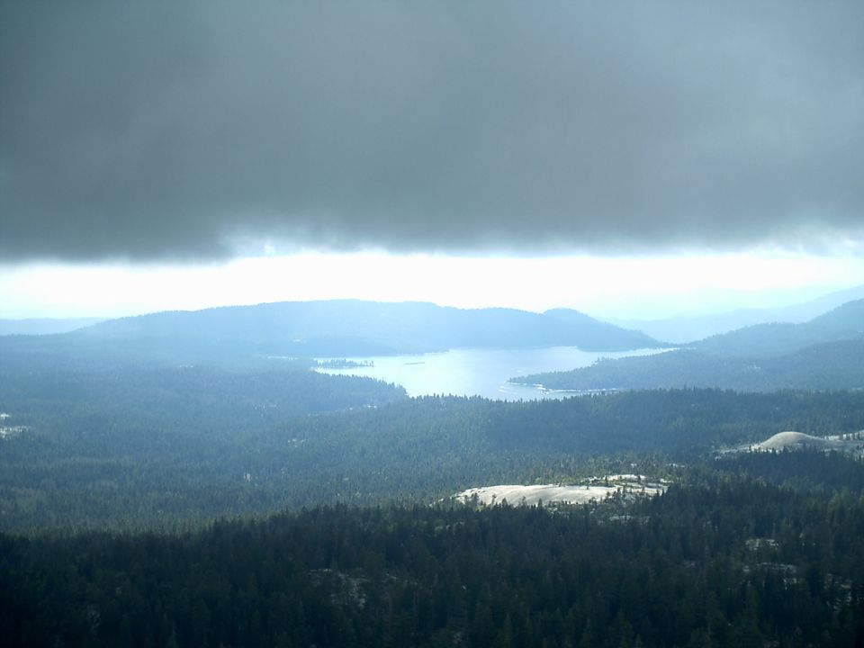 Lake surrounded by forested mountains under a cloudy sky