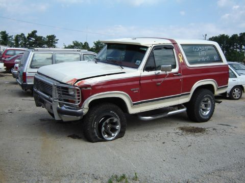 1986 Ford Bronco - This 1986 Ford Bronco has a flat tire and visible damage to the hood and front bumper.
