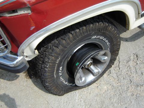 1986 Ford Bronco - A vehicle with a severely flat tire, revealing the wheel rim.