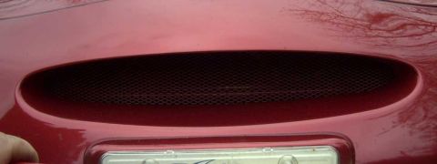 1997 Ford Taurus - Close-up of a red car's hood vent with a mesh grille. The registry claims it is a 1997 Ford Taurus, but this is not verifiable from the ima…
