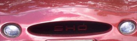 1997 Ford Taurus - Close-up of a red car's front grille, the 'SHO' emblem and headlights.