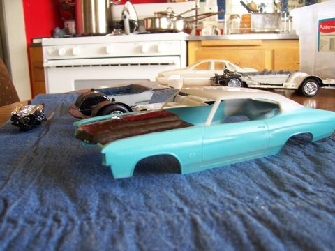 1995 Ford Bronco - Model car parts including a turquoise body, engine, and wheels are laid out on a blue cloth.