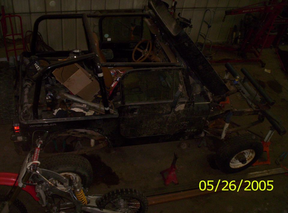 Jeep Wrangler with doors off and top removed, sitting in a garage