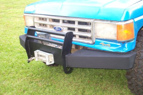 1987 Ford Bronco - Front view of a blue 1987 Ford Bronco, an aftermarket bumper, winch, and 4x4 badging.