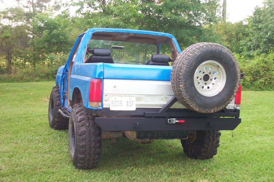 Blue Ford Bronco with a rear-mounted spare tire and aftermarket bumper