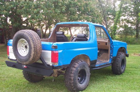 1987 Ford Bronco - This 1987 Ford Bronco features a bright blue exterior, a rear-mounted spare tire, and aftermarket sliders.