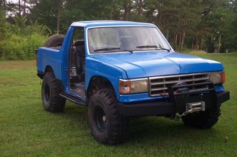 1987 Ford Bronco - This modified truck features large tires and a front-mounted winch, suggesting off-road use.