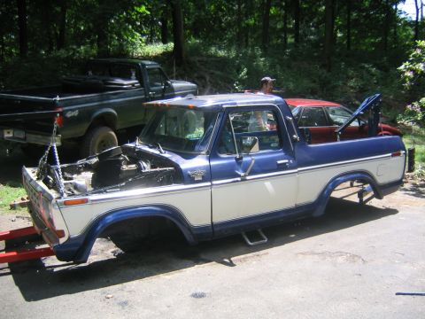 1978 Ford Bronco - Blue-and-white Ford Bronco body shell with Ranger trim and cab clearance lights sitting on the ground with its top, hood, wheels and frame…