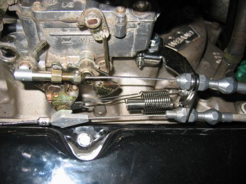 1985 Ford Crown Victoria LTD - Carburetor linkage and throttle cables with a prominent return spring are visible in this close-up engine shot.