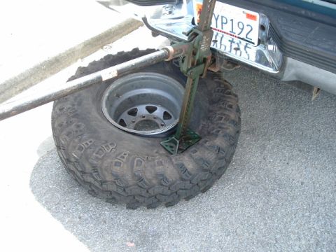 1989 Ford Bronco - A vehicle's rear tire is being lifted by a jack, with a license plate visible.
