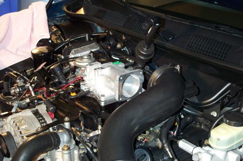 1998 Ford Crown Victoria - The engine bay shows a modified intake manifold and throttle body, with various hoses and electrical components visible.