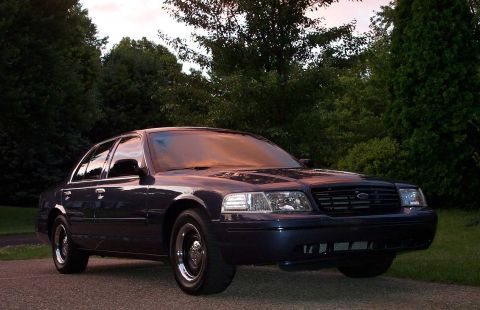 1998 Ford Crown Victoria - Dark blue 1998 Ford Crown Victoria parked on a paved surface with trees in the background.