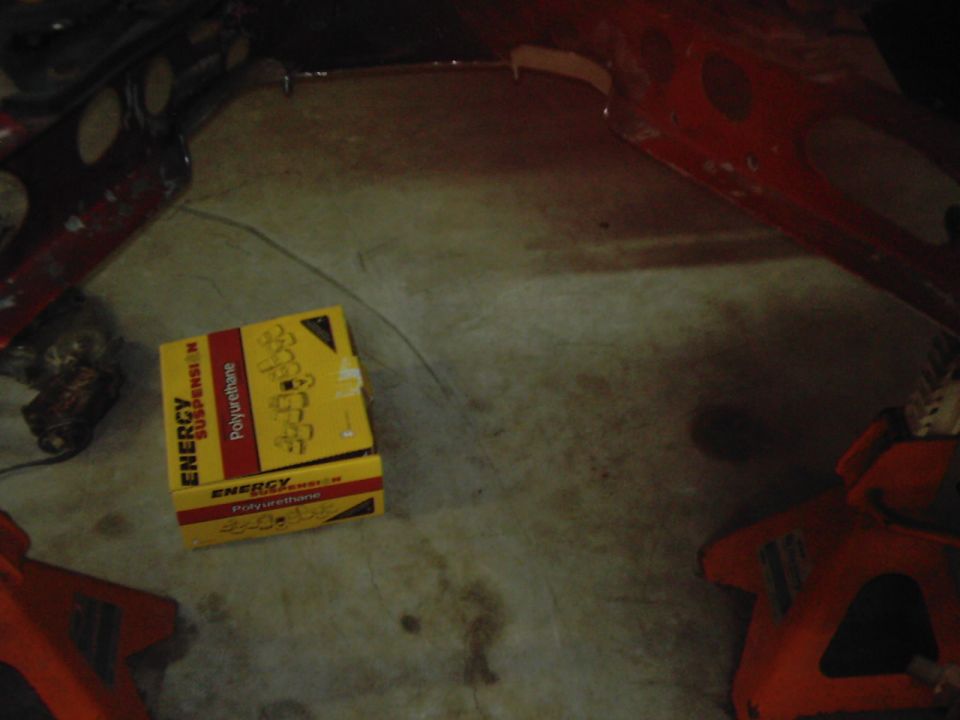 Yellow box labeled "ENERGY SUSPENSION Polyurethane" on concrete floor near red jack stands