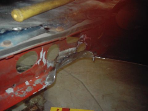 1978 Ford Bronco - Detail shot of a vehicle's frame showing areas of rust and recent repair work, with a yellow tool in the background.