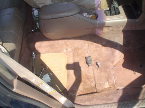 1995 Ford Taurus - Interior view of a car's passenger side floor, with tools scattered near the center console.