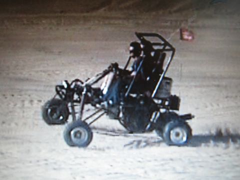 1990 Ford Bronco - tube-frame single-seat off-road dune buggy with a roll cage driven across open desert sand.