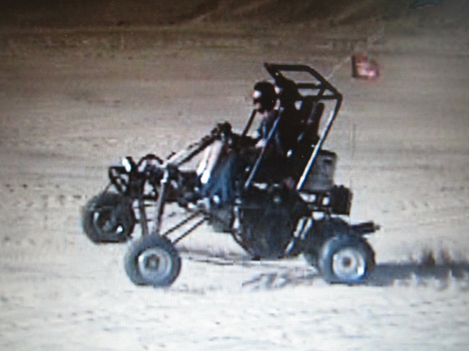 Single-seat off-road dune buggy with roll cage driving on sand