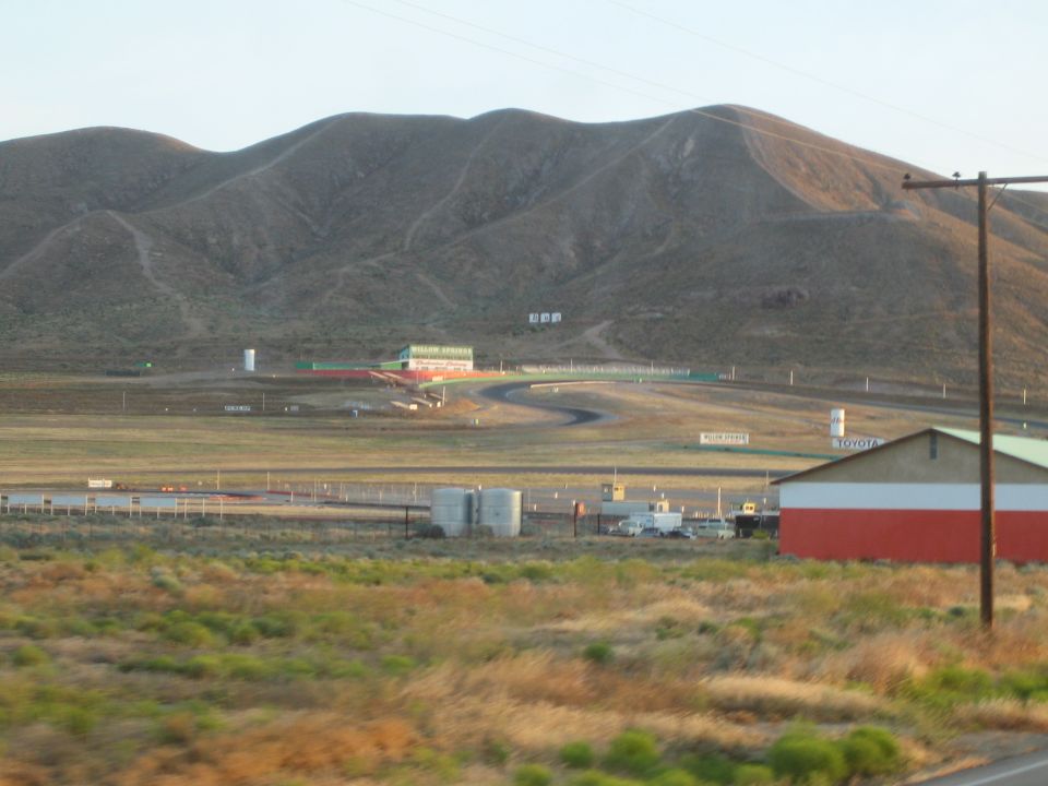Distant view of racetrack infield and buildings below dry brown mountains