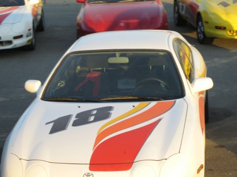 1990 Ford Bronco - Front view of a white Toyota race coupe wearing number 18 and red-and-orange flame side graphics in a paddock.