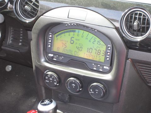 1990 Ford Bronco - AIM MXL digital racing dash display fitted into a car's center console above the climate-control knobs.