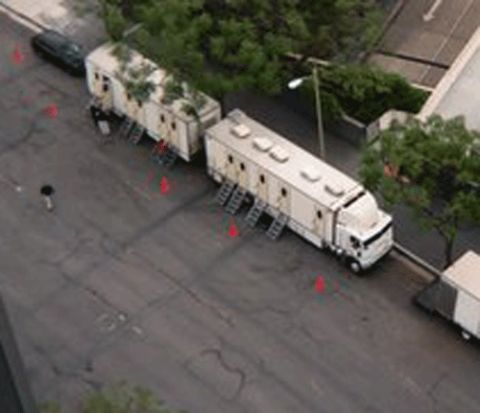1990 Ford Bronco - overhead shot shows long white production-style semi trailers parked along a paved lot marked with orange traffic cones.