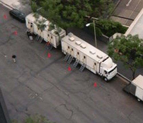Aerial view of white semi trailers parked on a paved lot with traffic cones