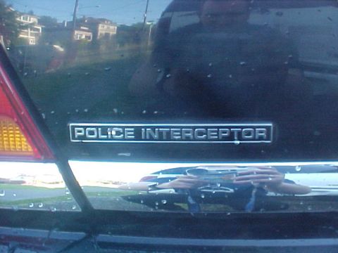 1999 Ford Crown Victoria - The rear of a dark-colored vehicle shows a "Police Interceptor" badge.