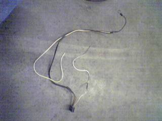 1990 Ford Bronco - A close-up view of a wiring harness lying on a concrete surface, with a Supermotors.net logo in the corner.