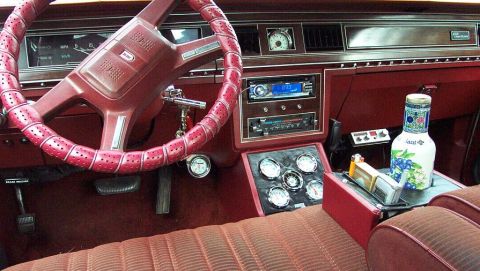 1985 Ford Crown Victoria LTD - The interior of a car shows a dashboard with multiple gauges and a red steering wheel.