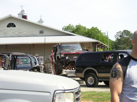 1996 Ford Bronco - Multiple off-road vehicles are parked near a building on a sunny day.