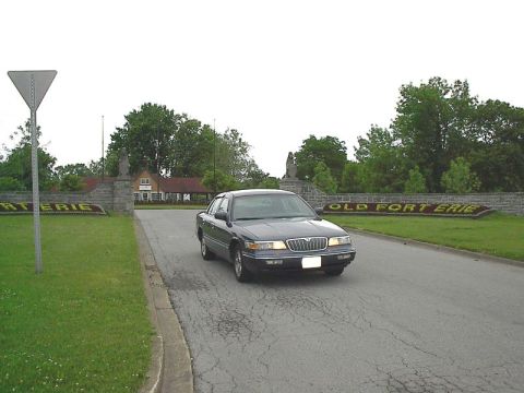 1985 Mercury Grand Marquis - A dark sedan drives past the Old Fort Erie entrance sign.