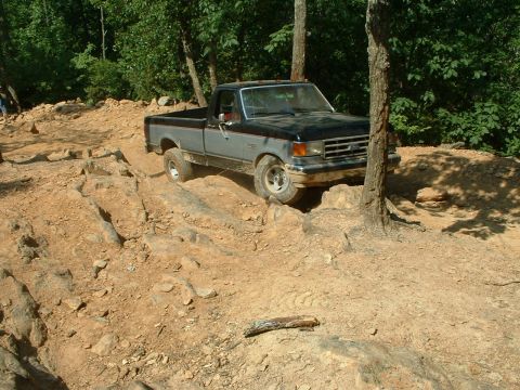 1985 Ford Bronco - Ford F-150 truck tackles a challenging rocky path in a wooded area.