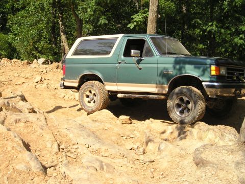 1996 Ford Bronco - A green 1996 Ford Bronco navigates a rocky off-road trail.