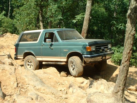 1985 Ford Bronco - This Ford Bronco is tackling a challenging off-road course with large rocks and steep inclines.