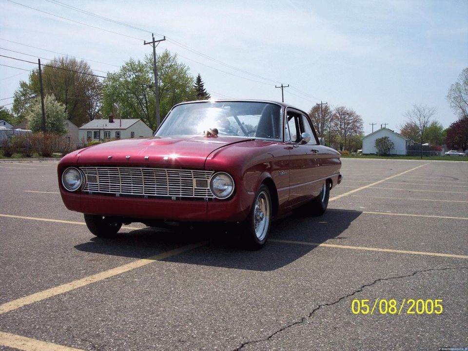 Candy red early Ford Falcon two-door drag car with skinny front tires in a parking lot