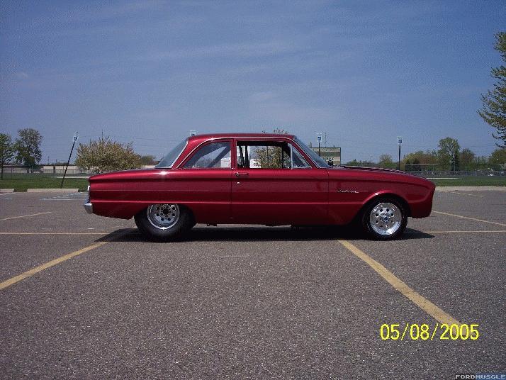 Candy red early-1960s Ford Falcon two-door in pro-street stance, side profile in a parking lot