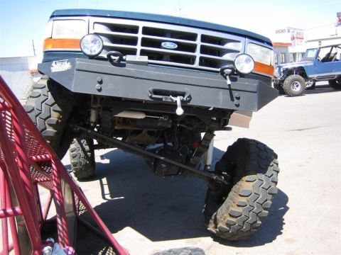 1994 Ford Bronco - This modified Ford truck features a custom bumper and off-road tires, with a Jeep in the background.