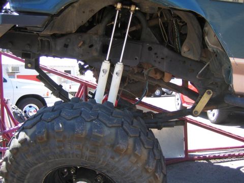 1994 Ford Bronco - The underside of a modified vehicle shows heavy-duty suspension components and a large off-road tire.