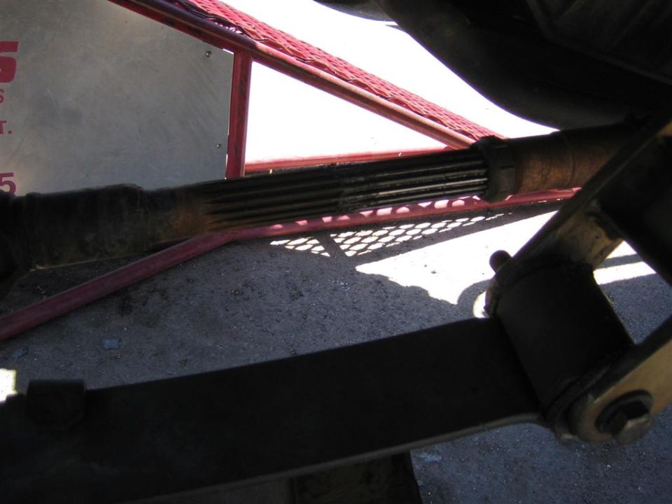 Close-up of a driveshaft with splines, part of a vehicle's suspension system visible