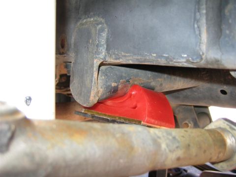 1994 Ford Bronco - Close-up of a red bump stop on a vehicle's frame, with visible rust on the surrounding metal parts.