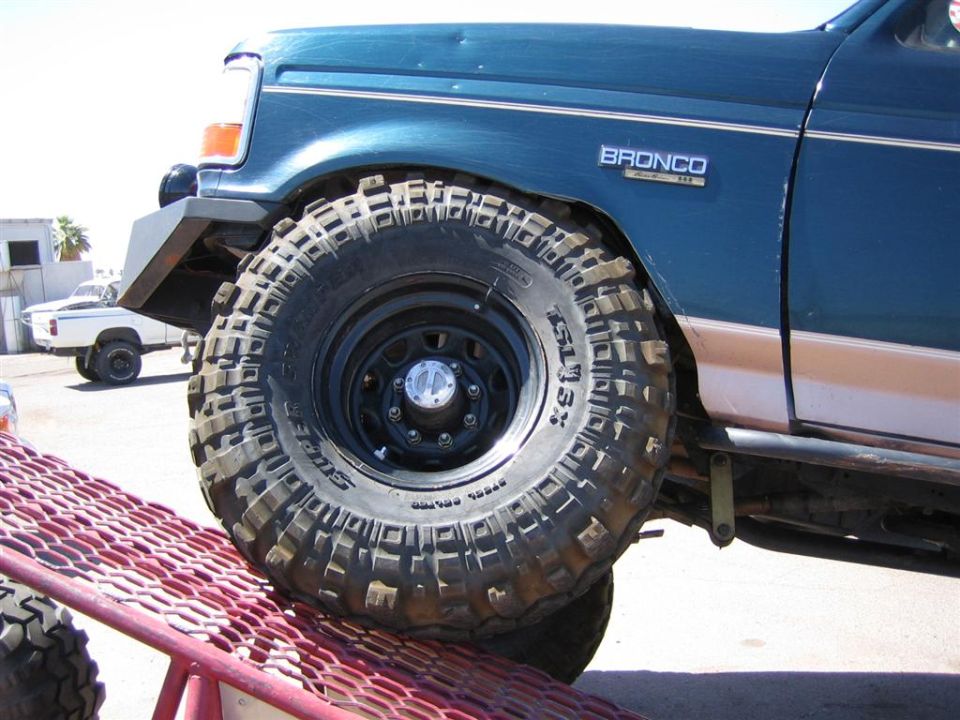 1994 Ford Bronco front fender and large off-road tire, with another white truck in the background
