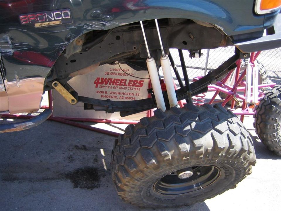 Close-up of a 1994 Ford Bronco's lifted suspension and large tire. A "4Wheelers" sticker is visible on the frame