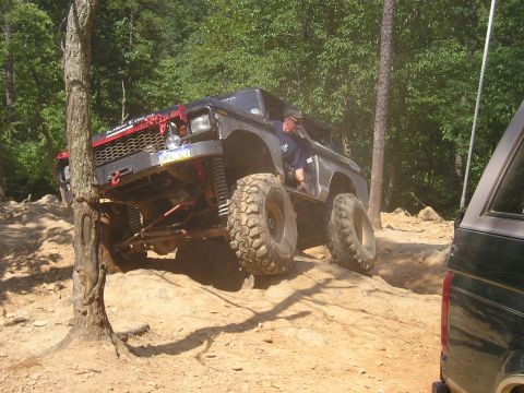 1996 Ford Bronco - A heavily modified SUV navigates a challenging off-road trail with large tires and lifted suspension.