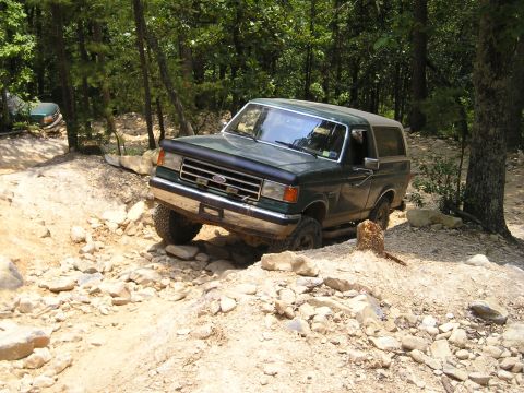 1996 Ford Bronco - Ford Bronco tackling a challenging rocky trail in a wooded area.