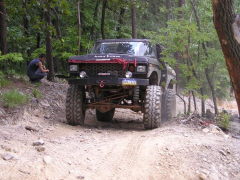 1996 Ford Bronco - A heavily modified Ford Bronco navigates a wooded off-road trail.