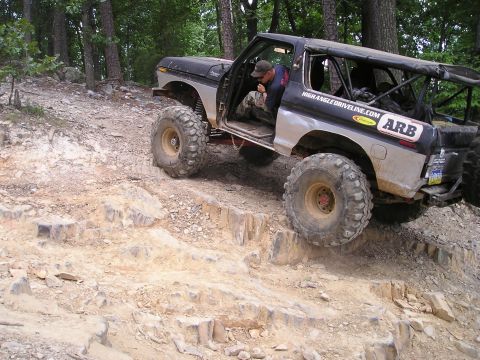 1996 Ford Bronco - This heavily modified 1978 Ford Bronco navigates a challenging rocky trail with large off-road tires and a roll cage.