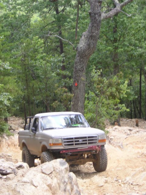 1996 Ford Bronco - A Ford Bronco navigates a rocky off-road course surrounded by trees.