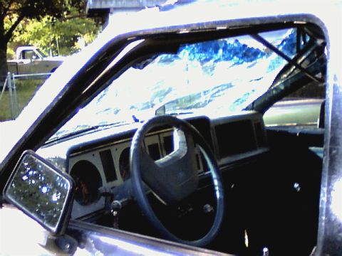 1987 Ford Bronco II - The interior of an older SUV is visible, with a reflection of mountains in the windshield.